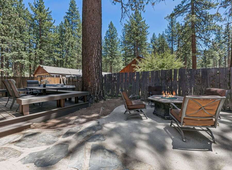 Enjoy outdoor living in this spacious backyard featuring a large deck with a dining set and a separate patio area with a fire pit and comfortable seating.