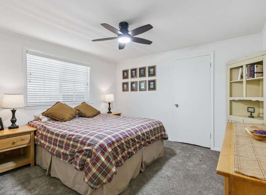 This charming bedroom features a comfortable queen-size bed adorned with a classic plaid comforter, perfect for a cozy retreat.