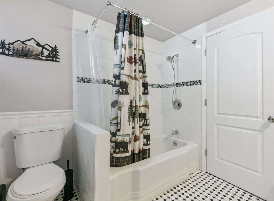 This charming bathroom features a classic white subway tile shower with a decorative black and white mosaic tile accent.