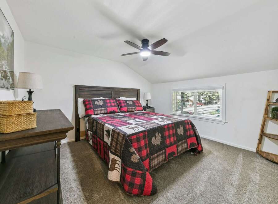 Experience rustic charm in this cozy bedroom, featuring a comfortable queen-size bed adorned with a lodge-themed quilt.