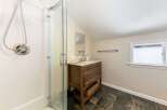 This bathroom features a sleek glass-enclosed shower and a charming wooden vanity with a marble countertop.