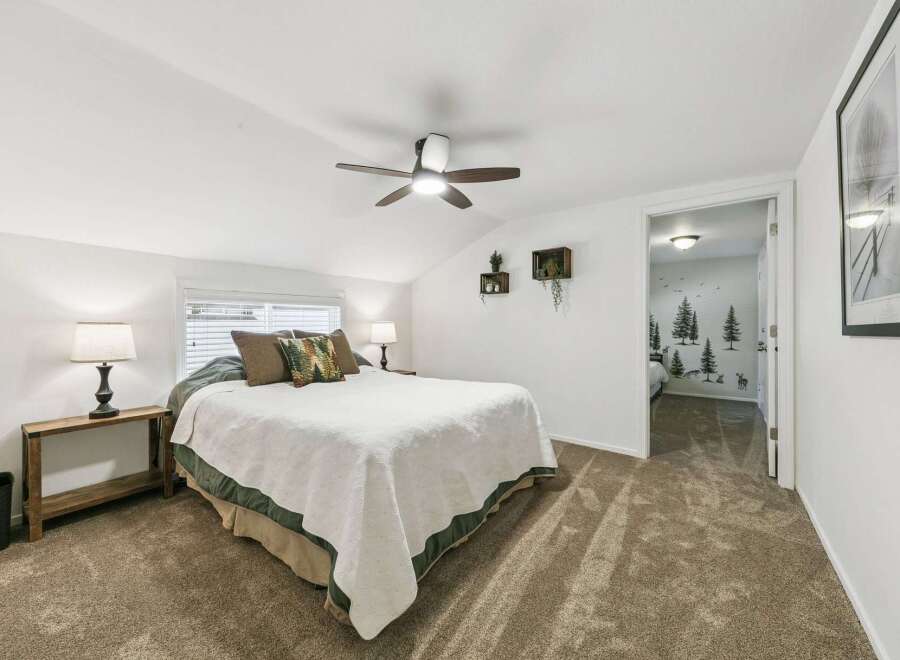 Discover this charming bedroom featuring a comfortable queen-size bed adorned with plush pillows and a cozy white quilt.