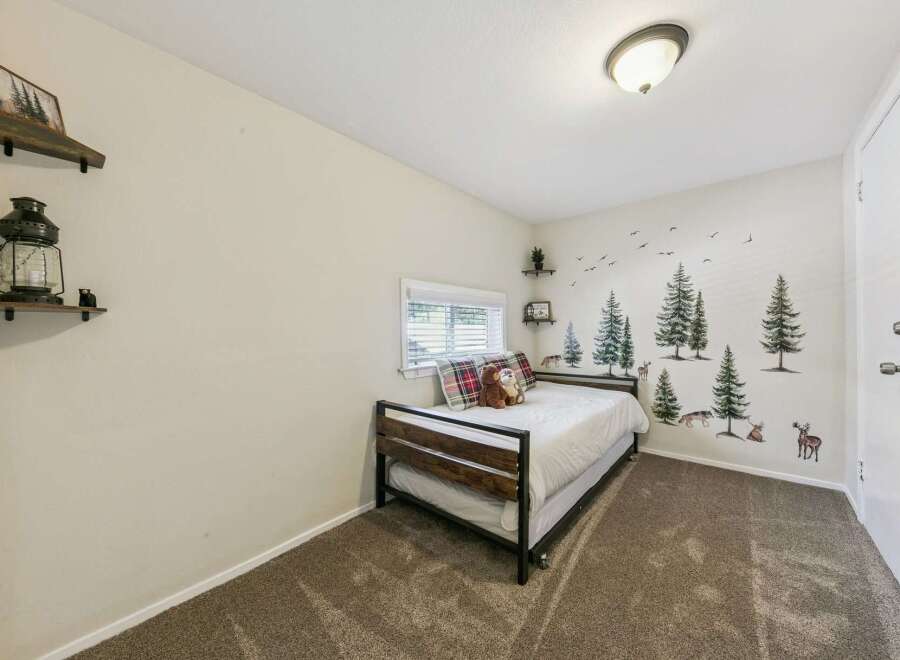 This charming bedroom features a cozy daybed with plaid pillows and a plush teddy bear, perfect for relaxation.