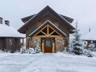 Experience the charm of this mountain retreat, featuring a rustic stone and wood facade perfect for a snowy landscape.