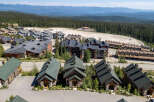Discover this charming mountain village featuring a collection of rustic cabins and multi-story lodges nestled amidst a dense evergreen forest.