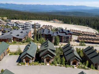 Discover this charming mountain village featuring a collection of rustic cabins and multi-story lodges nestled amidst a dense evergreen forest.