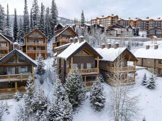Experience luxury mountain living in this stunning ski resort property, featuring charming wooden chalets nestled amidst snow-covered pine trees.
