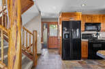 Experience rustic charm in this inviting entryway and kitchen area, featuring a grand log staircase and warm wooden cabinetry.