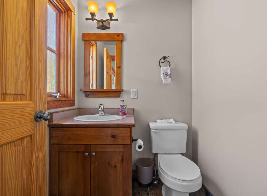 This charming bathroom features a rustic wooden vanity with a white sink and a chrome faucet, complemented by a matching wooden mirror frame.