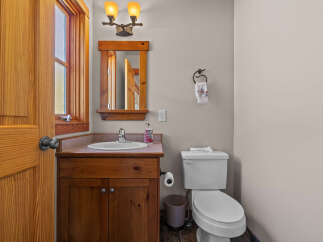 This charming bathroom features a rustic wooden vanity with a white sink and a chrome faucet, complemented by a matching wooden mirror frame.