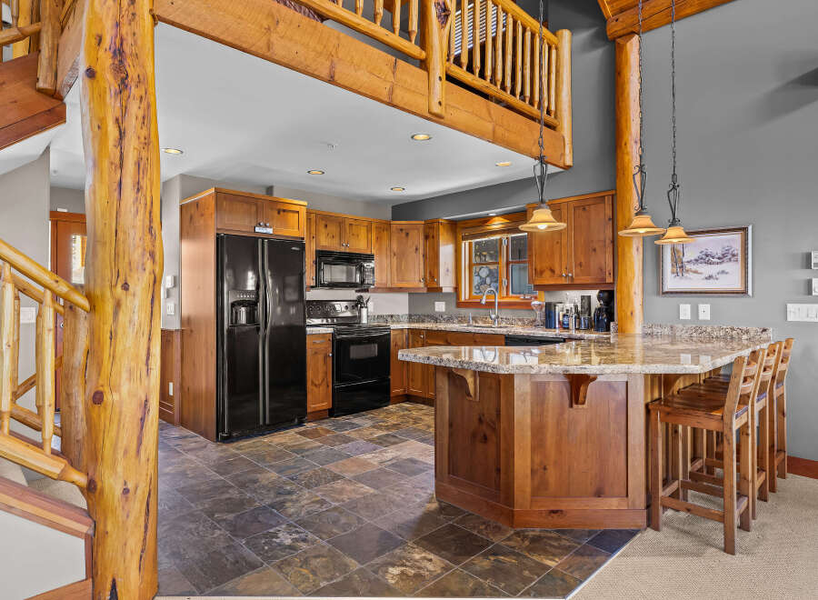 Experience rustic charm in this spacious kitchen featuring warm wood cabinetry and a large island with granite countertops, perfect for entertaining.