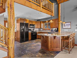 Experience rustic charm in this spacious kitchen featuring warm wood cabinetry and a large island with granite countertops, perfect for entertaining.