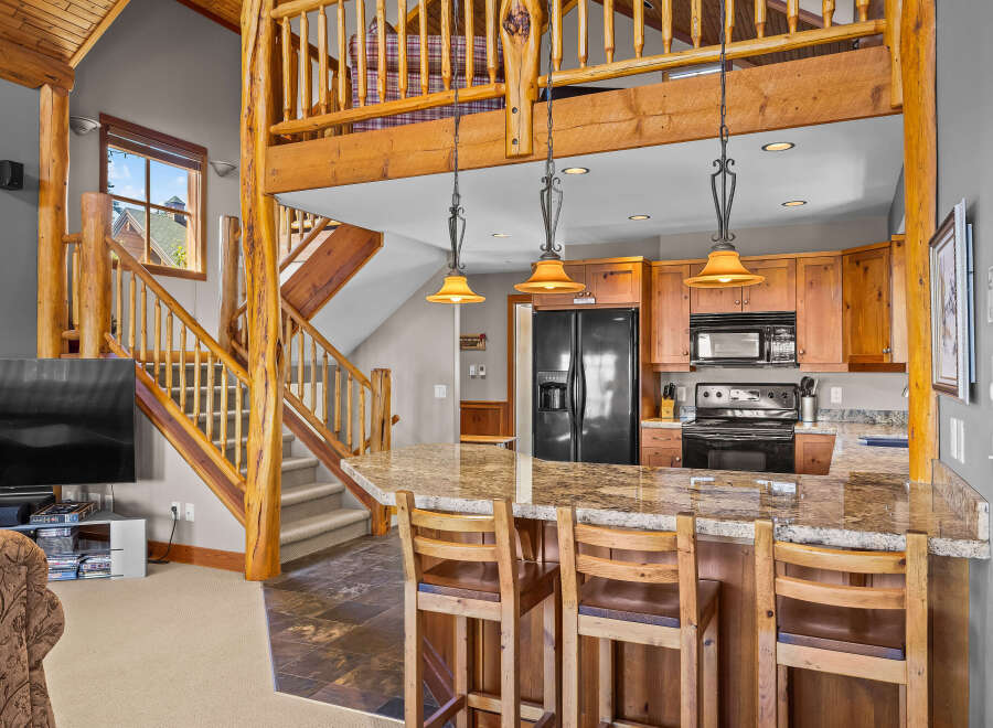 Experience rustic charm in this open-concept living space, featuring a stunning log-beam staircase leading to a loft.