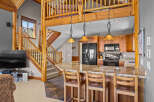 Experience rustic charm in this open-concept living space, featuring a stunning log-beam staircase leading to a loft.