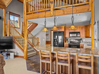 Experience rustic charm in this open-concept living space, featuring a stunning log-beam staircase leading to a loft.