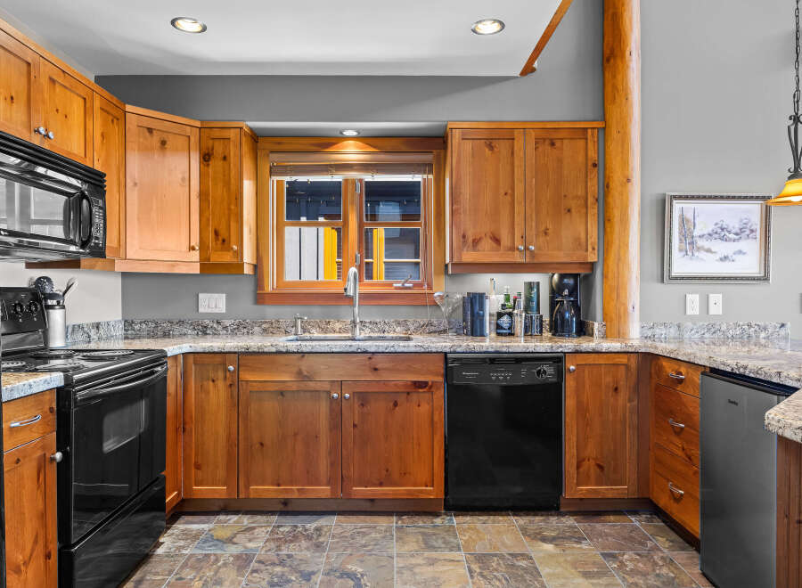 This charming kitchen features warm, natural wood cabinetry complemented by elegant granite countertops.