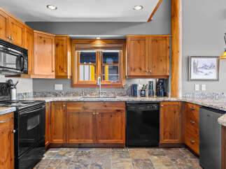 This charming kitchen features warm, natural wood cabinetry complemented by elegant granite countertops.