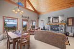 Experience breathtaking mountain views from this stunning living and dining area, featuring a cozy stone fireplace and a rustic wooden ceiling.