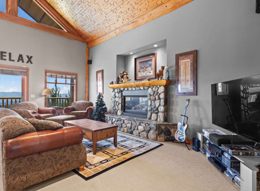 Experience ultimate relaxation in this cozy living room, featuring a stunning stone fireplace and a vaulted wood-beamed ceiling.