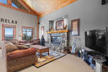Experience ultimate relaxation in this cozy living room, featuring a stunning stone fireplace and a vaulted wood-beamed ceiling.