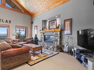 Experience ultimate relaxation in this cozy living room, featuring a stunning stone fireplace and a vaulted wood-beamed ceiling.