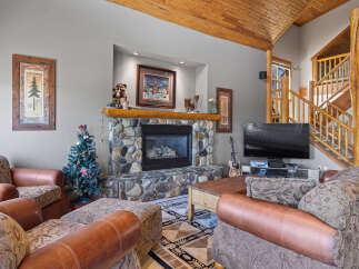Cozy up by the stone fireplace in this inviting living room, perfect for gathering with loved ones.