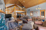 Experience rustic charm in this spacious living area featuring a soaring wood-paneled vaulted ceiling and a grand stone fireplace.