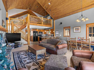 Experience rustic charm in this spacious living area featuring a soaring wood-paneled vaulted ceiling and a grand stone fireplace.