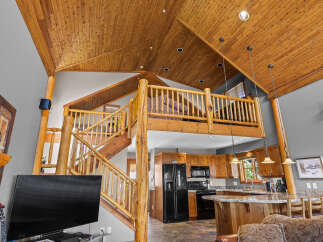 Experience rustic charm in this stunning log cabin-style home featuring a soaring wood-paneled vaulted ceiling and a beautiful loft overlooking the main living area.