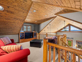 Experience ultimate relaxation in this cozy loft living space, featuring a plush red sofa and a rustic wood-paneled ceiling.
