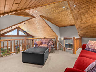 Experience rustic charm in this loft living area, featuring a vaulted wood-paneled ceiling and a cozy seating arrangement.