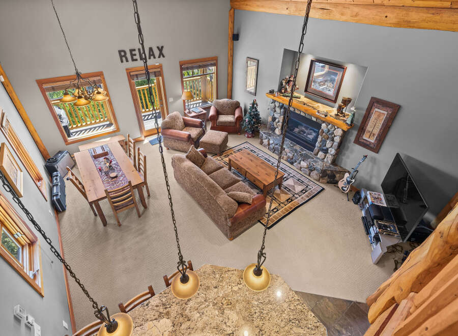Experience rustic charm in this spacious living area, featuring a grand stone fireplace and a cozy seating arrangement perfect for gatherings.