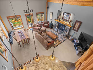 Experience rustic charm in this spacious living area, featuring a grand stone fireplace and a cozy seating arrangement perfect for gatherings.