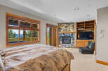 Experience ultimate comfort in this luxurious bedroom, featuring a stunning stone fireplace and a large window with breathtaking mountain views.