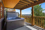 Enjoy ultimate relaxation on this covered deck featuring a spacious hot tub with stunning mountain views.