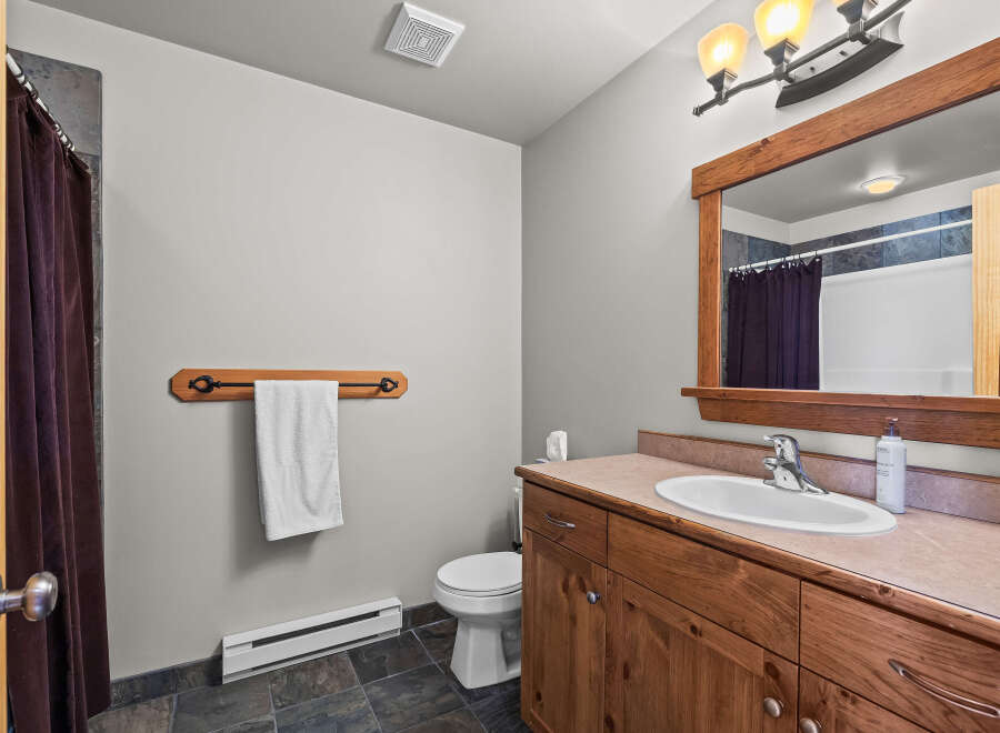 This bathroom features a rustic wooden vanity with a white sink and chrome faucet, complemented by a large wooden framed mirror.
