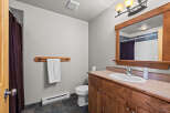 This bathroom features a rustic wooden vanity with a white sink and chrome faucet, complemented by a large wooden framed mirror.