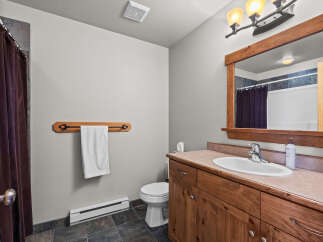 This bathroom features a rustic wooden vanity with a white sink and chrome faucet, complemented by a large wooden framed mirror.