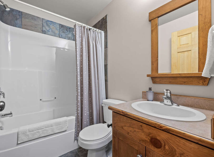 This charming bathroom features a pristine white bathtub with a sleek chrome showerhead and a decorative tiled accent wall.