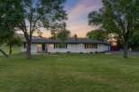 This charming white ranch-style home offers a picturesque setting with mature trees and a spacious lawn.