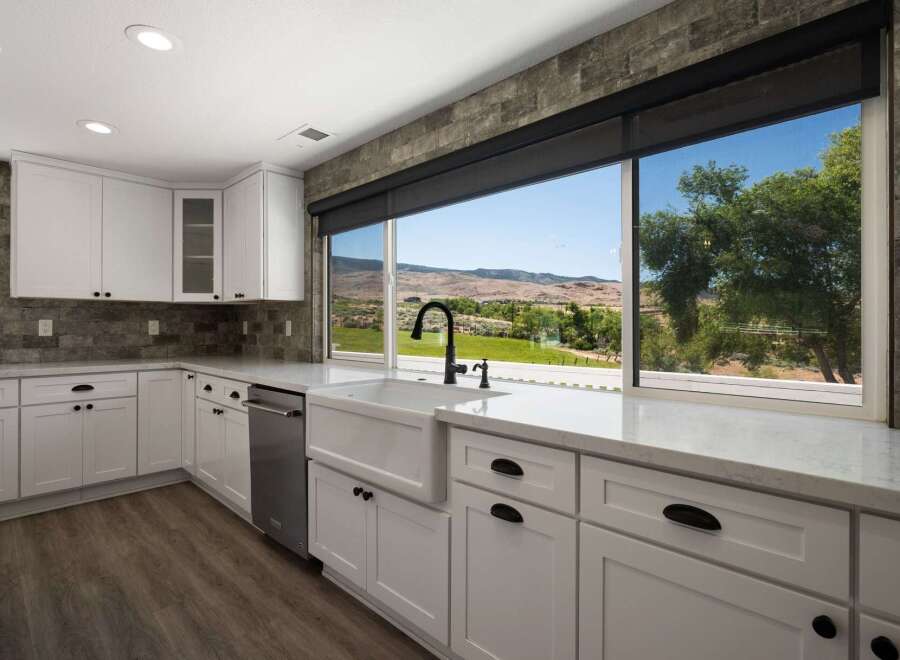 Experience breathtaking views from this stunning kitchen, featuring a large farmhouse sink and sleek white cabinetry.