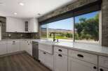 Experience breathtaking views from this stunning kitchen, featuring a large farmhouse sink and sleek white cabinetry.