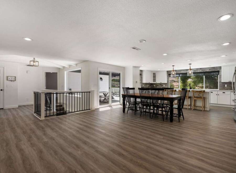 Discover this spacious open-concept living area, perfect for entertaining, featuring a large dining table and a modern kitchen with ample cabinet space.