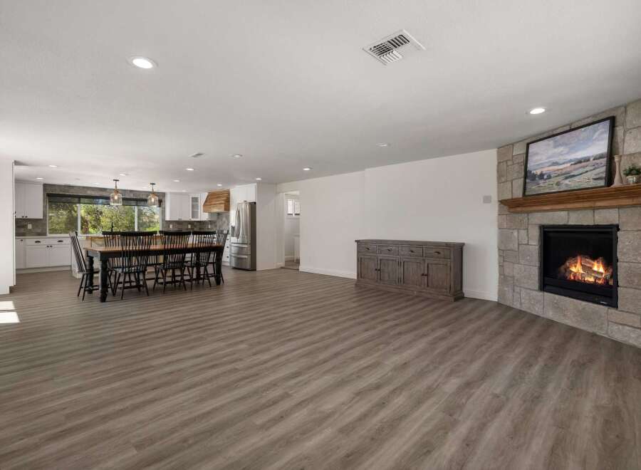 Experience open-concept living in this spacious home, featuring a large dining area perfect for gatherings and a cozy living space centered around a stone fireplace.