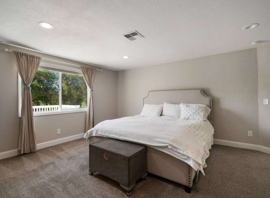 This inviting bedroom features a plush upholstered headboard and a comfortable bed adorned with crisp white linens.