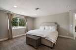 This inviting bedroom features a plush upholstered headboard and a comfortable bed adorned with crisp white linens.