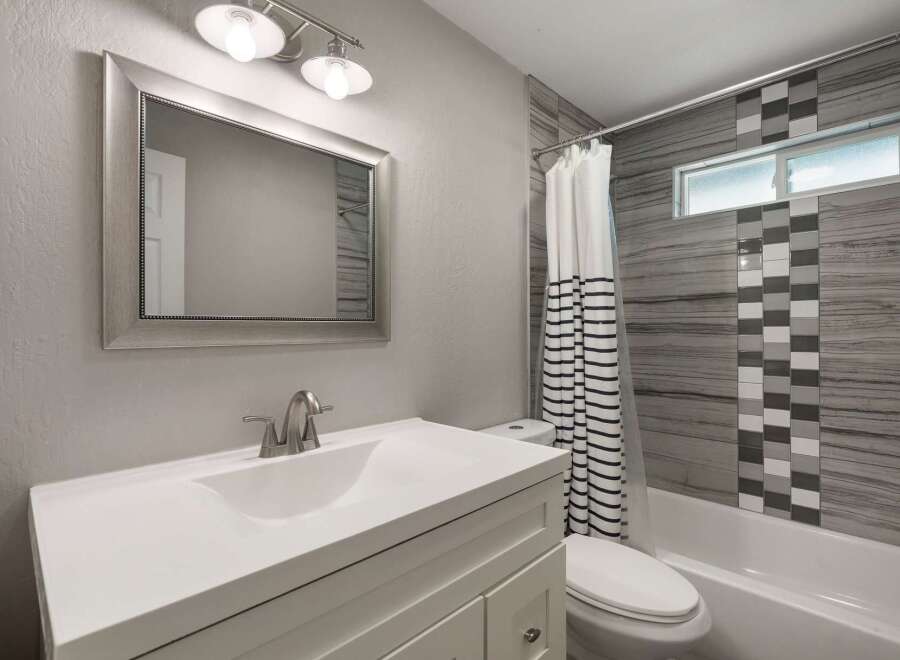 This modern bathroom features a sleek white vanity with a matching sink and a brushed nickel faucet.