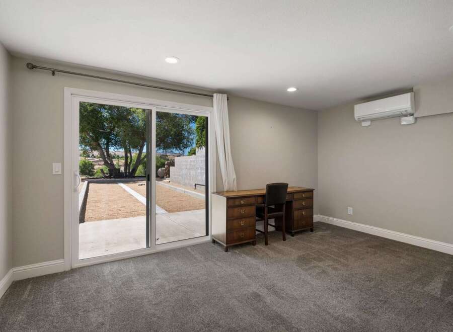 This spacious room features a large sliding glass door that opens to a serene outdoor space, perfect for enjoying the natural surroundings.