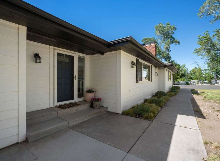 Welcome to this charming home featuring a classic white exterior with a dark-trimmed roof and a welcoming front porch.