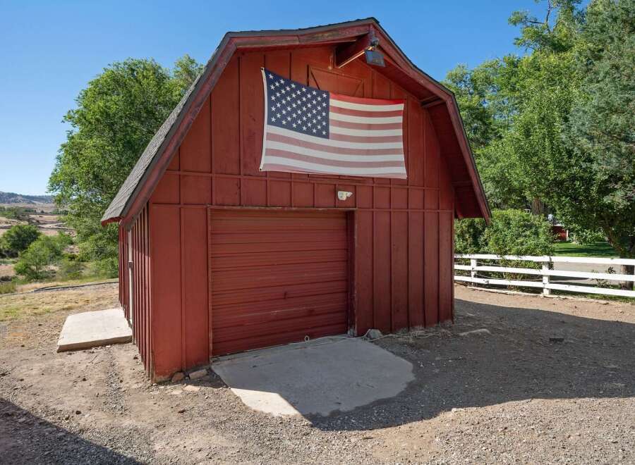 Showcasing a charming red barn with a prominent American flag displayed on its facade, this property offers a rustic and patriotic aesthetic.